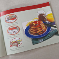 Hot cakes with butter and syrup on a blue plate and a glass of tea on a beige surface