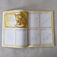 Open book showing a drawing tutorial with step-by-step instructions on a gray surface