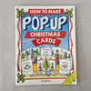 Book titled 'How to Make Pop-Up Christmas Cards' by Kingfisher on a grey textured background