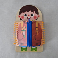 Getting dressed game for children to practice zips, buckles, buttons and clips with a character design on the cover, featuring a face and outfit, on a gray background.