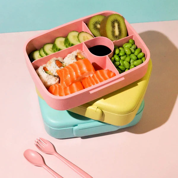 Colourful bento box with food compartments on a pink background
