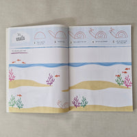 Open book with illustrations of snails, shells, and coral on a textured surface
