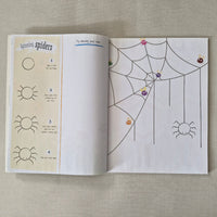 Open book with spider web and sun illustrations on a textured surface