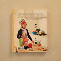 The back cover of a cookbook titled 'I want to be a chef' displayed flat against a textured beige background. Features a bright kitchen, with text describing the cooking show and recipes inside.