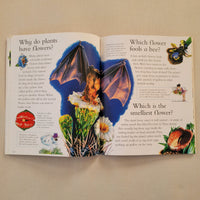 An open children's science book spread on a beige fabric background, featuring colorful illustrations of a bee, a bat, flowers, with educational text.