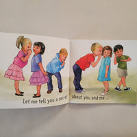 An open children's book spread showing two illustrated pages with drawings of children and printed text, photographed on a light fabric surface.