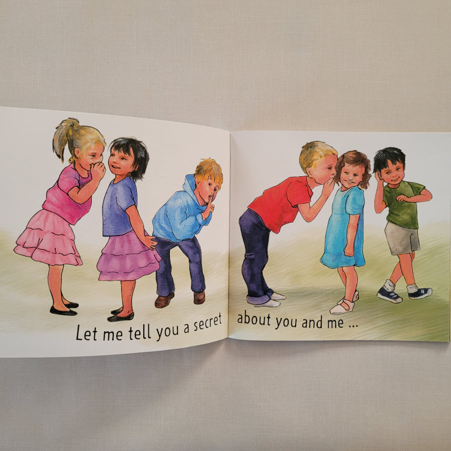 An open children's book spread showing two illustrated pages with drawings of children and printed text, photographed on a light fabric surface.