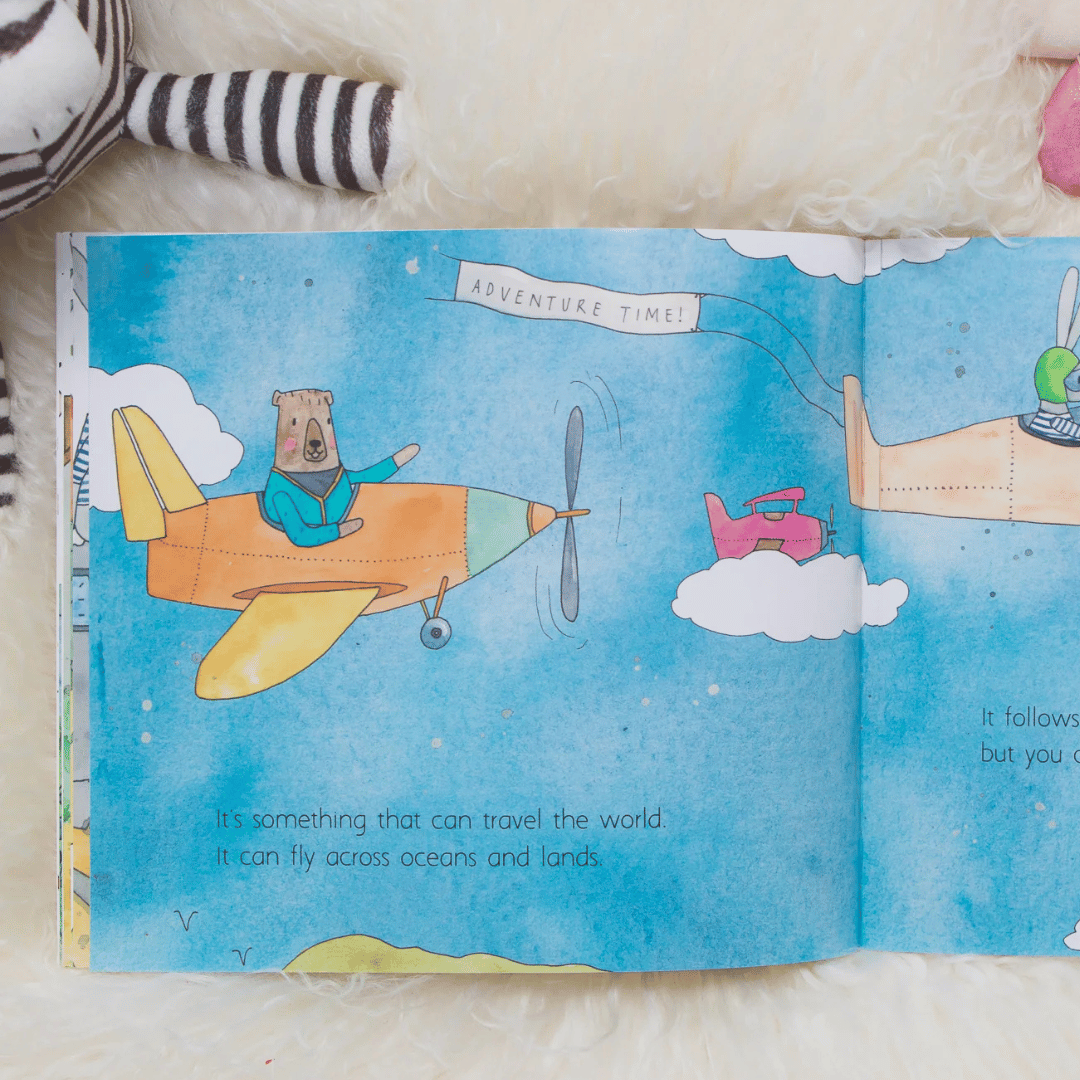 Open book with a colourful illustration of a bear on an airplane, surrounded by clouds and another airplane.