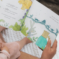 Child reading a children's book with illustrations of animals and text.