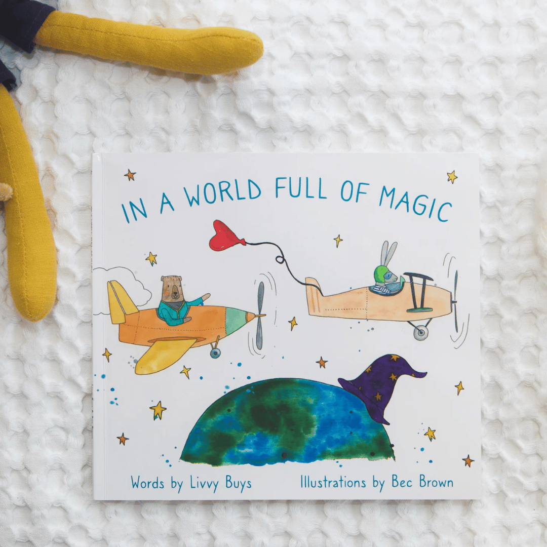 Children's book titled 'In a World Full of Magic' with illustrations of airplanes and a planet on a textured white surface.