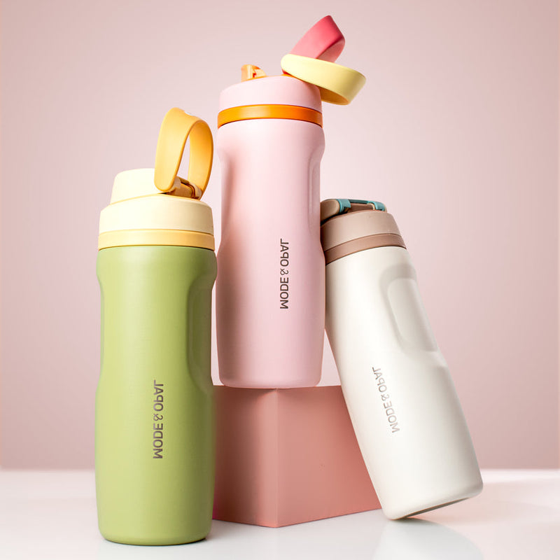 Three colorful water bottles with 'MODE & COAL' branding on a light pink background