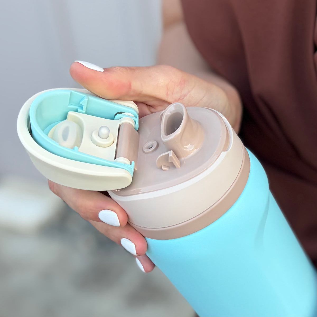 Hand holding a blue and beige water bottle