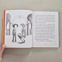 Open book with a illustration of two children by an archway against a beige background.