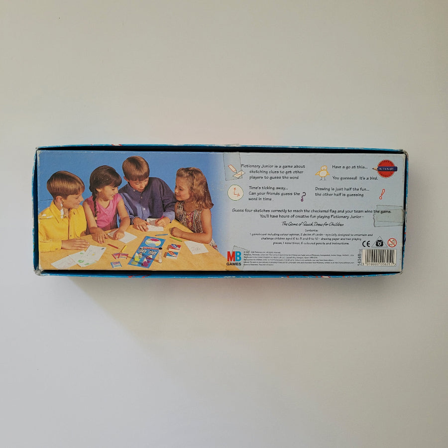 Back of Junior Pictionary game box with children playing on a table against a white background