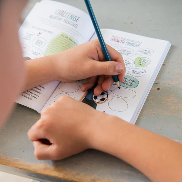 Child's hands holding a pen over an open book on a wooden surface