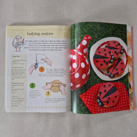 Open book with illustrations of ladybug cookies and a recipe on a textured surface