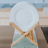 White plate on a wooden stand with a geometric-patterned eco cloth as a mat in a kitchen setting