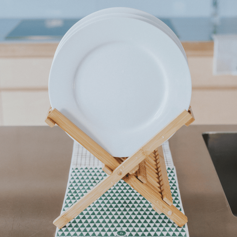 White plate on a wooden stand with a geometric-patterned eco cloth as a mat in a kitchen setting