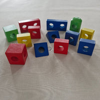 Colourful wooden blocks with holes on a light fabric background