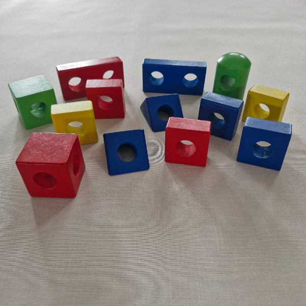 Colourful wooden blocks with holes on a light fabric background