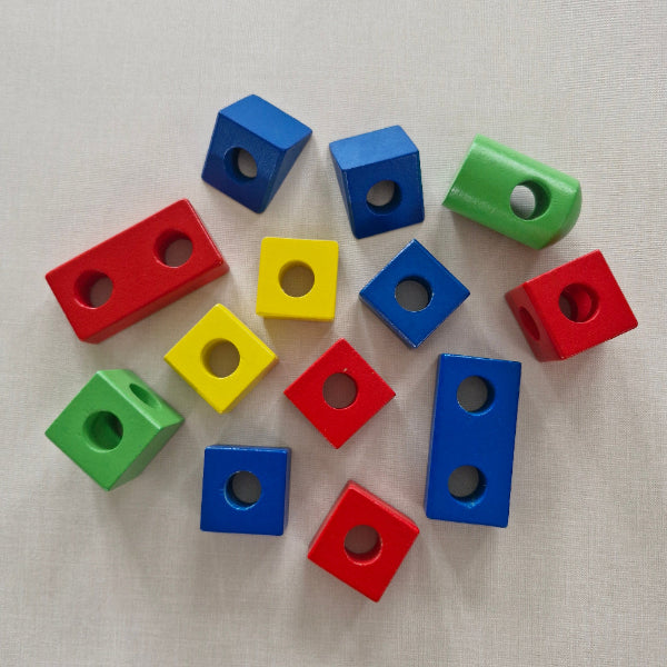 Colourful geometric threading blocks with holes on a beige surface