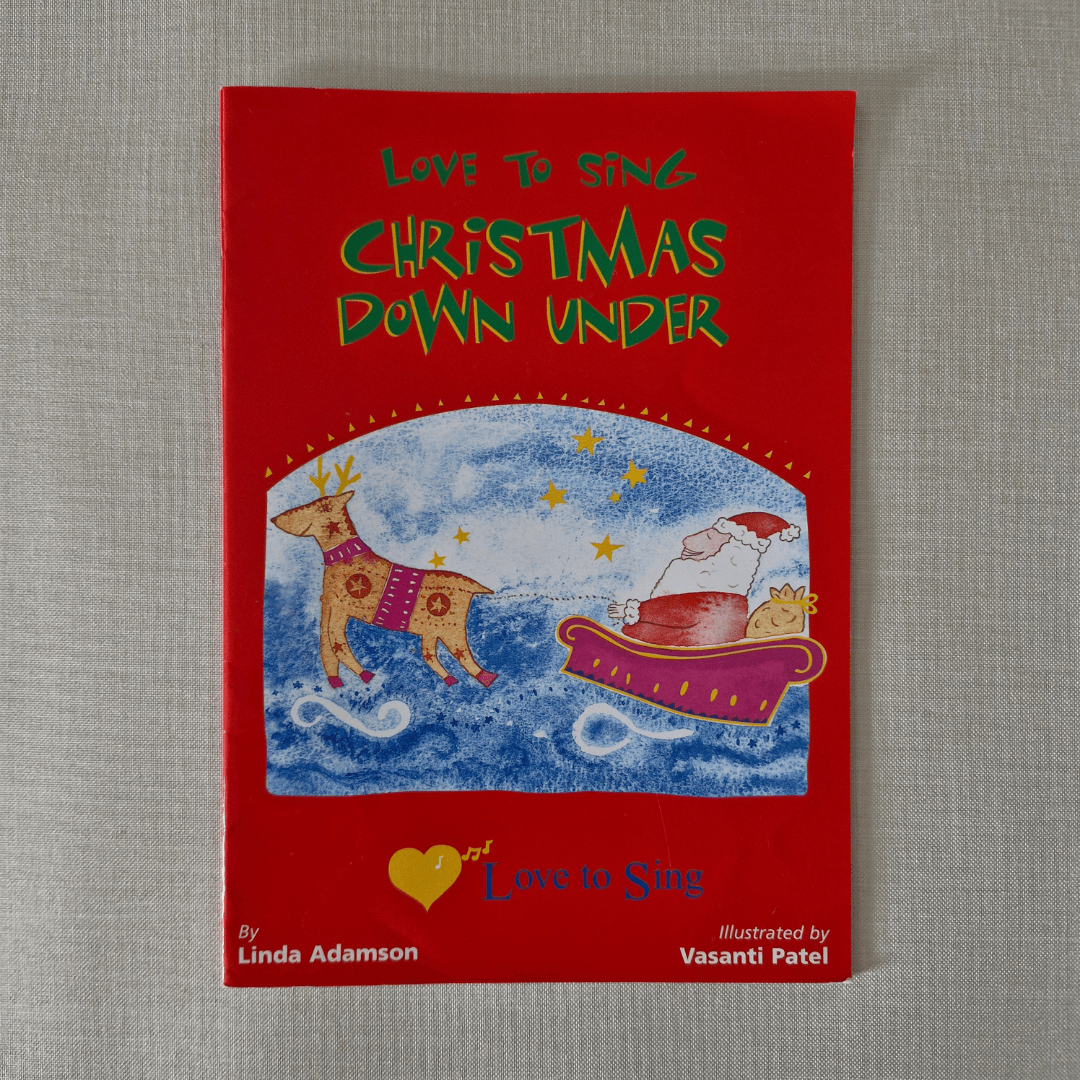 Red book cover titled 'Love to Sing Christmas Down Under' with illustrations of a dog and a reindeer on a grey background.