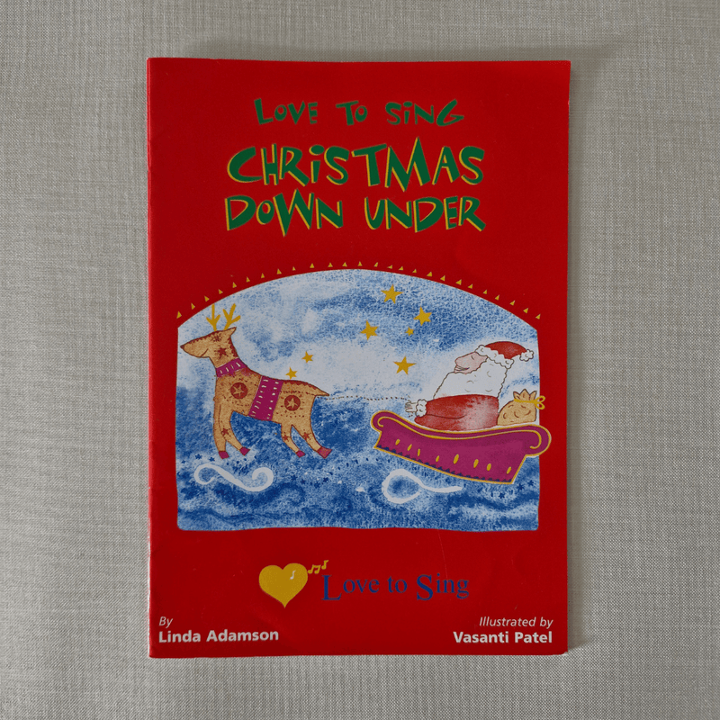 Red book cover titled 'Love to Sing Christmas Down Under' with illustrations of a dog and a reindeer on a grey background.