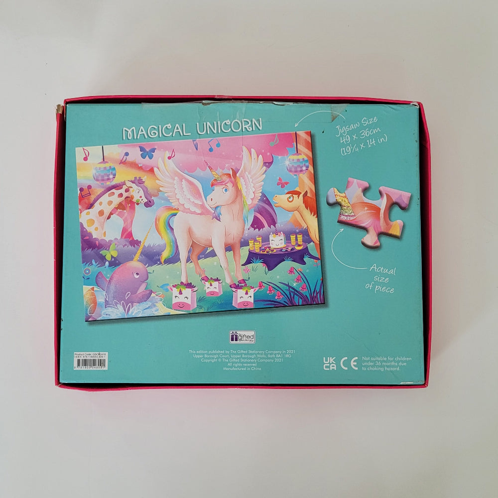 A jigsaw puzzle box labeled 'MAGICAL UNICORN' shown from the back, featuring a colourful illustration of a pink unicorn, a giraffe, a dog, and other fantasy animals on a turquoise background. The box has a red inner border and includes text noting 100 pieces.