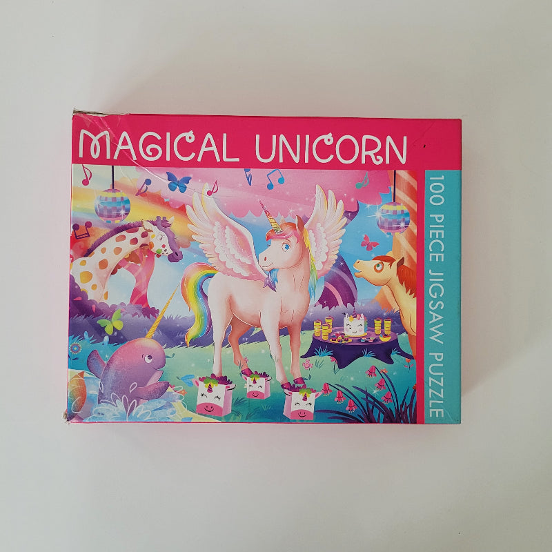 A 100-piece jigsaw puzzle box titled 'MAGICAL UNICORN' featuring a colorful illustration of a pink winged unicorn with a rainbow mane, set against a plain off-white background.