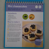 Recipe book page for mini cheesecakes with a plate of cheesecakes and blueberries.