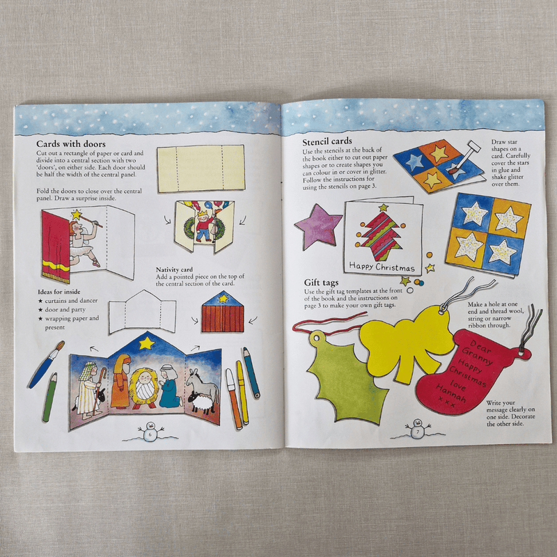 Open book with Christmas-themed craft activities on a grey surface