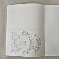 Open book with Christmas-themed cut-card on a textured fabric background