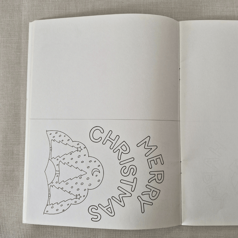 Open book with Christmas-themed cut-card on a textured fabric background