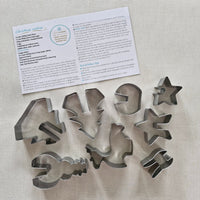 Set of metal cookie cutters with shapes on a light fabric background
