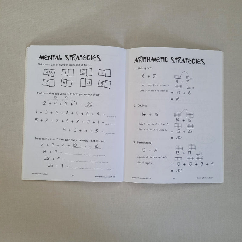 Two pages from a maths book with arithmetic strategies on a beige surface