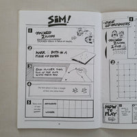 Black and white game instructions in maths book on a textured surface