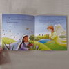 Open book showing illustrations of a woman and an angel in a pastoral setting.