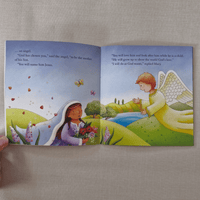 Open book showing illustrations of a woman and an angel in a pastoral setting.