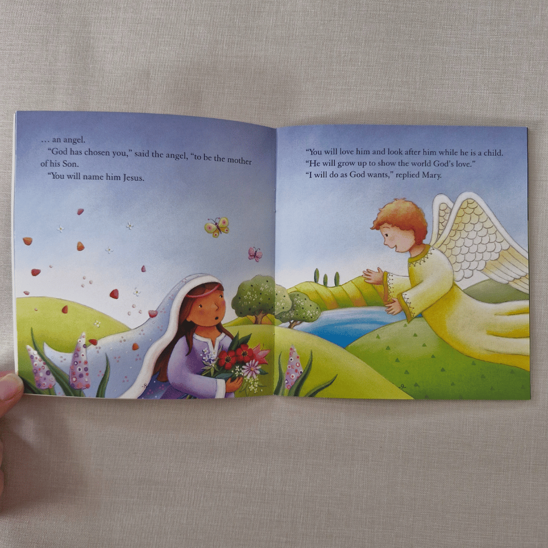 Open book showing illustrations of a woman and an angel in a pastoral setting.