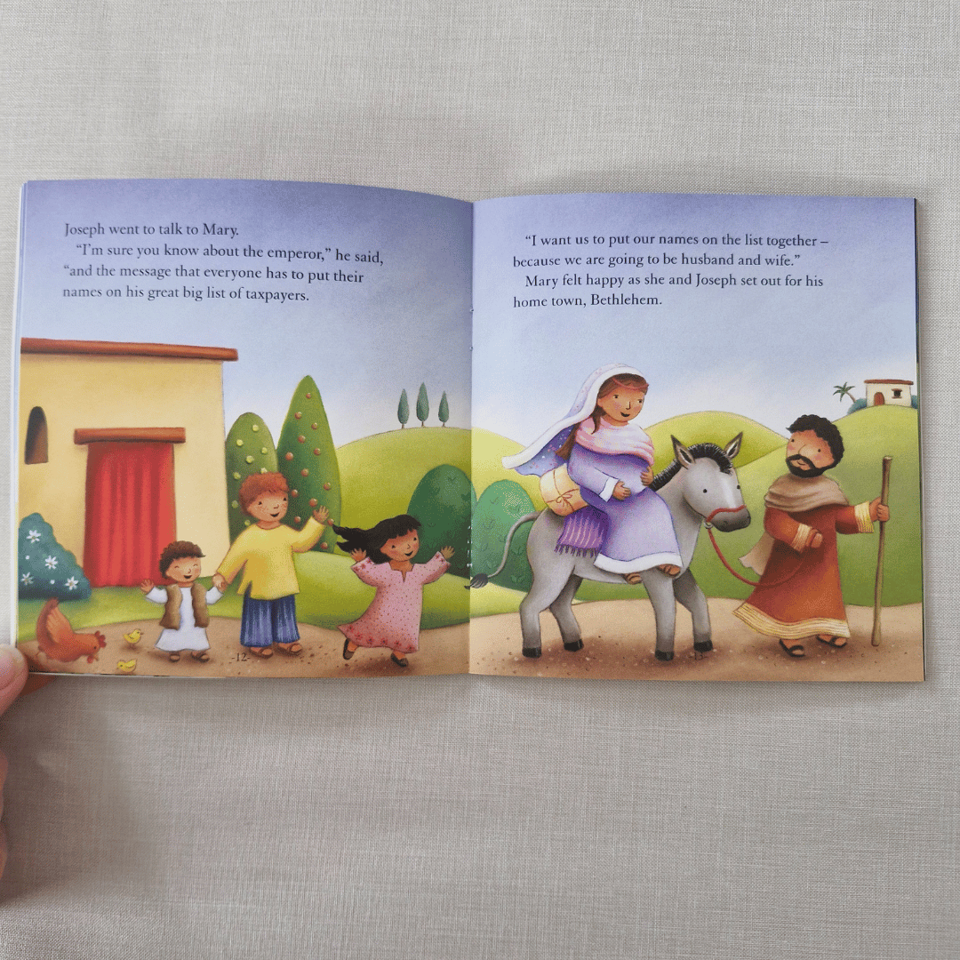 Open children's book with illustrations of a family and a donkey on a grey surface