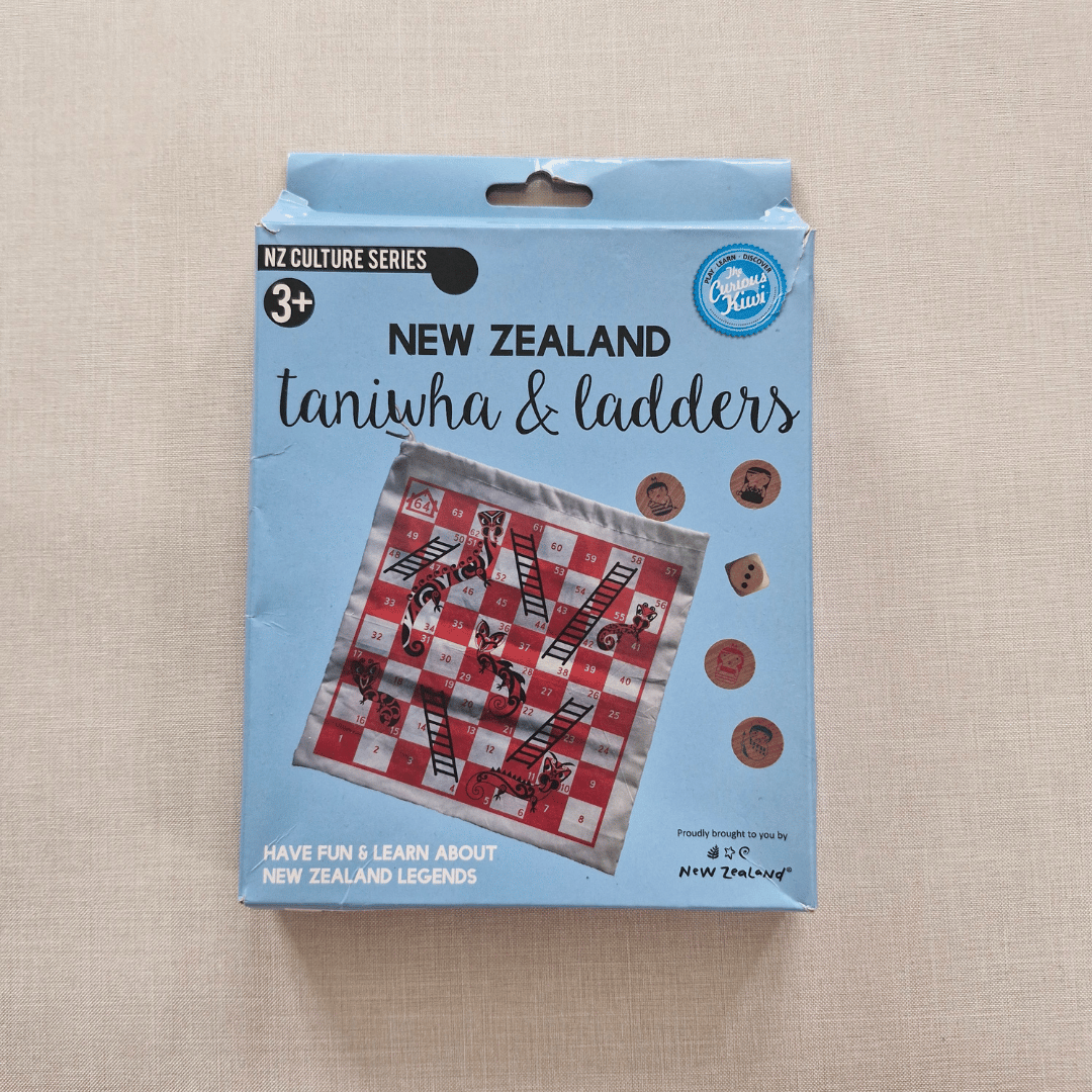 Packaging of New Zealand taniwha & ladders game on a beige background