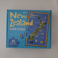 A blue box for a New Zealand floor puzzle, showing the product title, piece count, and a printed illustration of the New Zealand map on the front.