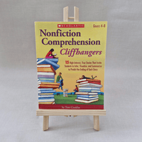 Book titled 'Nonfiction Comprehension Cliffhangers' by Scholastic on a wooden stand against a grey background