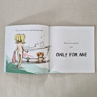Open book showing a cartoon illustration of a child in a bathtub on a beige background.