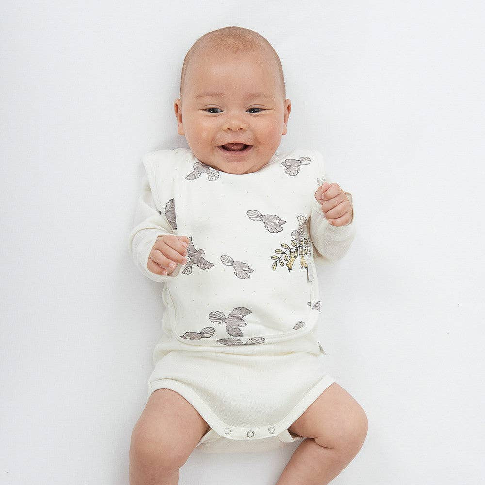 Baby wearing a white outfit with gray fantail pattern on a white background