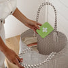 Person holding a woven basket with a green card featuring a white symbol.