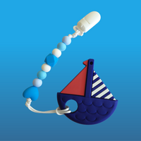 Sailboat-shaped teether on a blue pacifier clip with colorful beads on a blue background