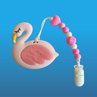 Pink flamingo-shaped teether on a pacifier clip with a string on a blue background