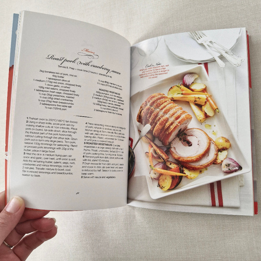 Open cookbook showing a recipe with sliced roasted meat and vegetables on a plate.