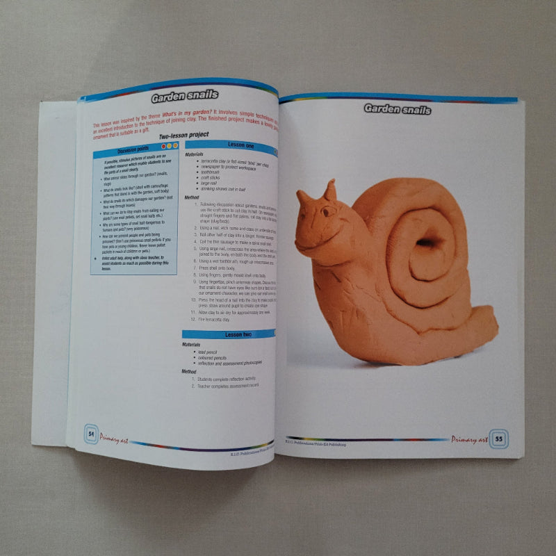 Open book with a clay snail model on a gray background